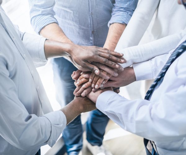 Close up view of young business people putting their hands together. Stack of hands. Unity and teamwork concept.